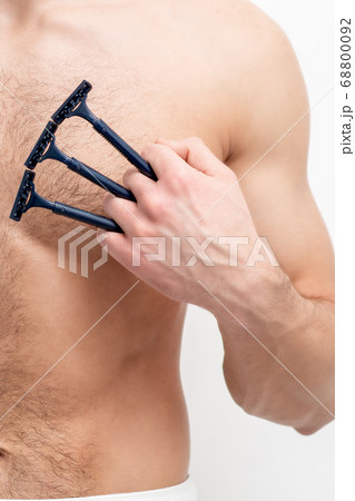 Young man shaving his chest Young man shaving his chest 68800092