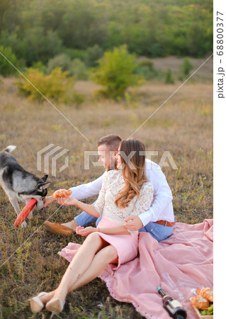 Young caucasian girl and boy sitting on grass and playing with husky. Young caucasian girl and boy sitting on grass and playing with husky. 68800377