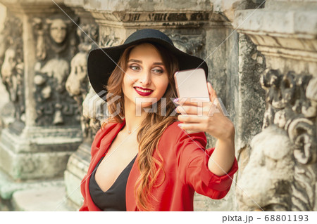 Pretty tourist girl is taking a selfie. 68801193