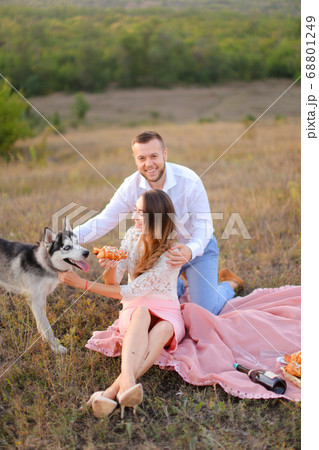 Young girl and boy sitting on pink plaid near husky and resting. 68801249