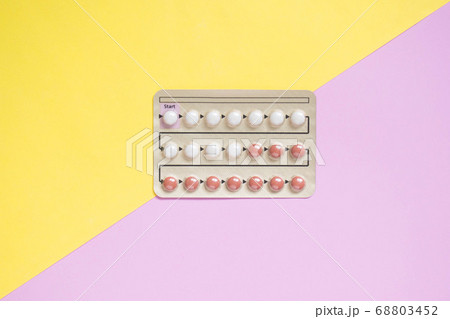 Oral contraceptive pills blister on yellow pink background. Hormones used to prevent pregnancy and treat other medical conditions, such as PCOS, endometriosis, amenorrhea or acne. Gynecology concept. Oral contraceptive pills blister on yellow pink background. Hormones used to prevent pregnancy and treat other medical conditions, such as PCOS, endometriosis, amenorrhea or acne. Gynecology concept. 68803452