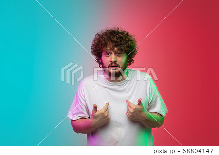 Caucasian young man's portrait on gradient studio background in neon 68804147