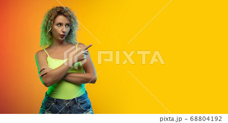 Caucasian young woman's portrait on gradient studio background in neon 68804192