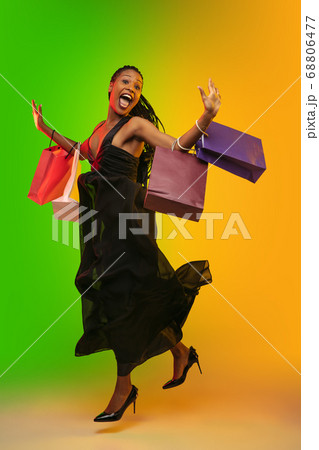 Portrait of young woman in neon light on gradient backgound. The human emotions, black friday, cyber monday, purchases, sales, finance concept. 68806477