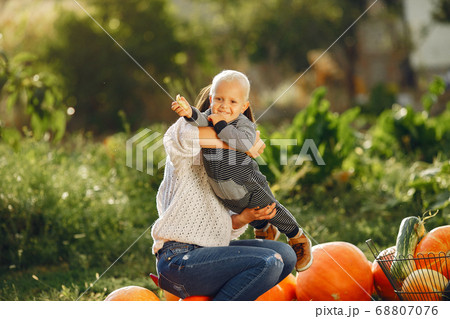 Mother and son sitting on a garden near many pumpkins Mother and son sitting on a garden near many pumpkins 68807076
