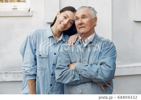 Old man standing on gray backround with his granddaughter Old man standing on gray backround with his granddaughter 68809332