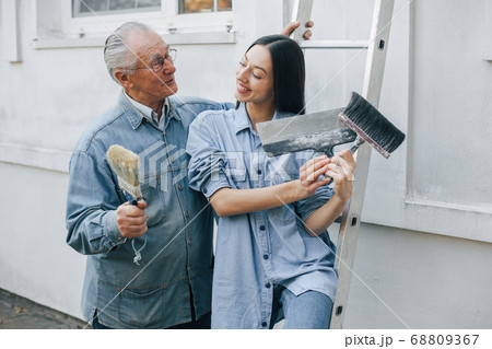 Family standing near building with repair tools 68809367