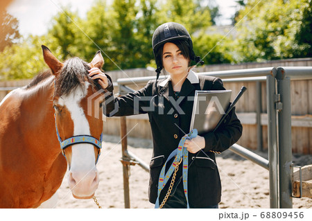 Beautiful woman standing with a horse 68809456