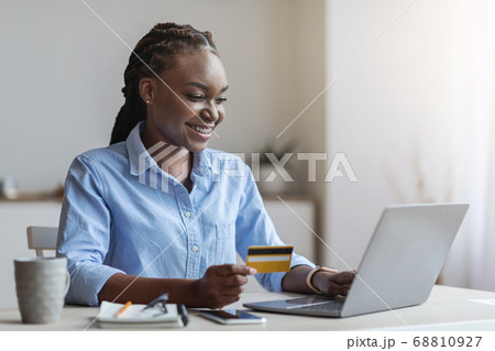 Young black businesswoman shopping online with laptop in office, using credit card 68810927