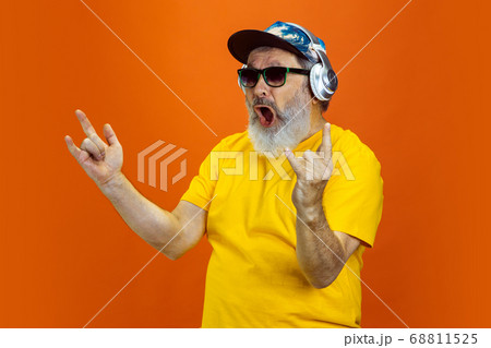 Senior hipster man using devices, gadgets on orange background. Tech and joyful elderly lifestyle concept 68811525