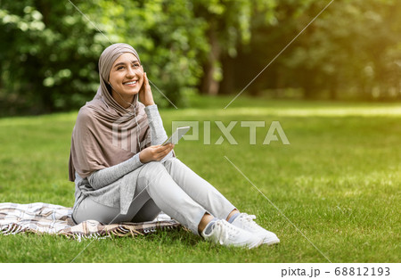 Joyful muslim girl listening to music, using smartphone Joyful muslim girl listening to music, using smartphone 68812193