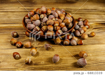 Hazelnuts in ceramic plate on a wooden table 68813339