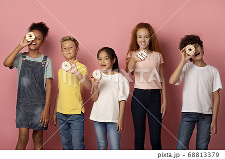 Joyful multiethnic schoolkids with tasty donuts over pink background 68813379