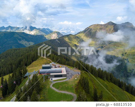 Aerial view on Kohlmais mountain station in Saalbach Austria as starting point for mountainbike trails and hikers in summer with great mountain panorama in the clouds 68813510