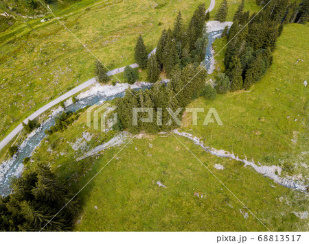 Aerial view on trees, paths and a creek used by people for refreshment in the skiing region of Hinterglemm in the Alps in Austria on a sunny summer day 68813517