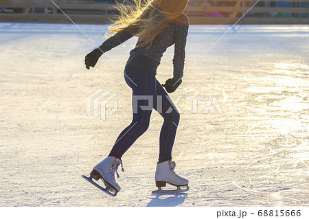 Girl with long hair skates on an ice rink Girl with long hair skates on an ice rink 68815666