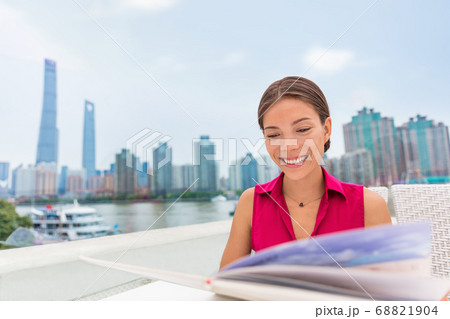 Asian woman eating at Shanghai waterfront outdoor restaurant looking at menu choosing meal for dinner. Chinese girl eating local food at the Bund, famous tourist attraction. 68821904