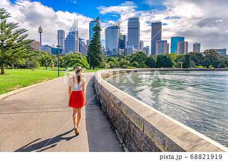 Sydney city girl tourist walking in urban park with skyscrapers skyline in the background. Australia travel vacation in the summer. Australian people lifestyle living. Sydney city girl tourist walking in urban park with skyscrapers skyline in the background. Australia travel vacation in the summer. Australian people lifestyle living. 68821919