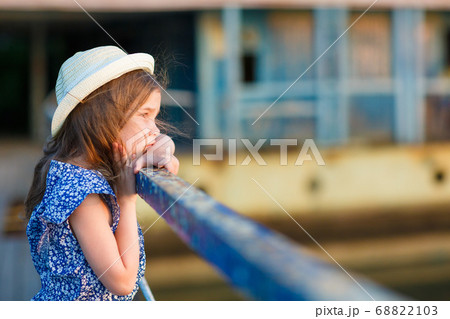 little girl standing on porch of old ruined house. 68822103