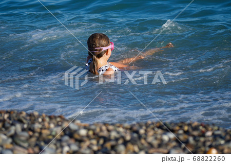 Little girl swims in the waves on the coast 68822260