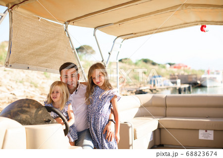 dad with kids helm boat on pier. tour on water 68823674