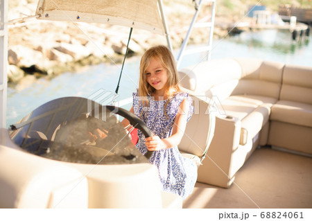 kid girl at helm of boat on pier. travel on water. kid girl at helm of boat on pier. travel on water. 68824061
