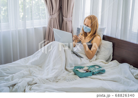 Woman lies in bed and has an online consultation with doctor GP 68826340