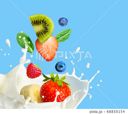 Fruit and berry falling in milk and splashing isolated on blue background. Smoothie or milkshake prepearing. 68830154