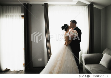 Beautiful bride and groom embracing and kissing on their wedding day 68833397