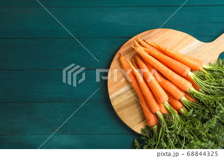 Cutting board with ripe carrots on wooden table 68844325