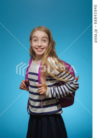 Little Caucasian girl with a school backpack on a blue background 68845940