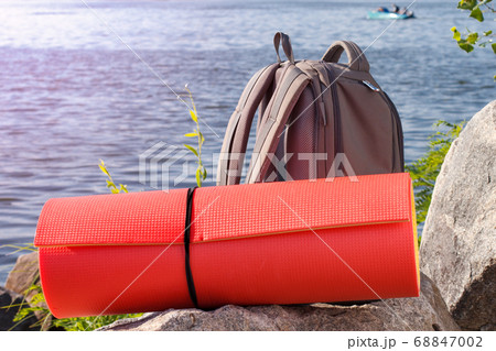 Hiking backpack and camping mat on rock with river 68847002