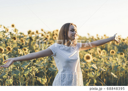Young beautiful woman having fun in a sunflower field 68848395