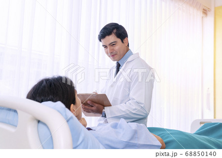 Hospitalized young woman lying in bed while doctor 68850140