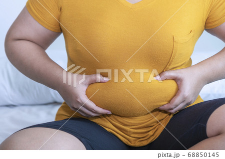 Overweight young woman pinches fat on her belly 68850145