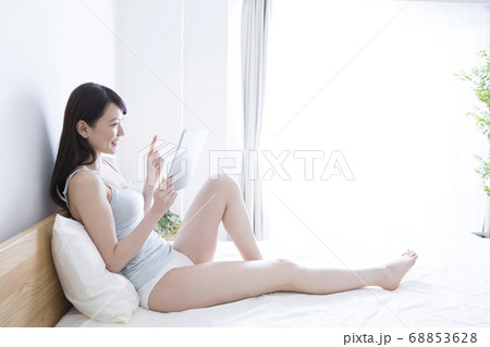 ベッドでタブレットPCを見る女性 68853628