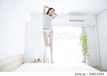 ベッドでジャンプする女性の写真素材