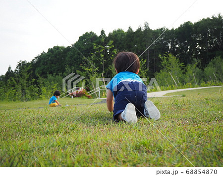 公園の芝生の上で兄弟で遊びながらはいはいする子供 68854870