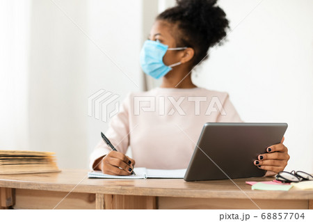 Black Schoolgirl In Surgical Mask Sitting Using Tablet In Classroom Black Schoolgirl In Surgical Mask Sitting Using Tablet In Classroom 68857704