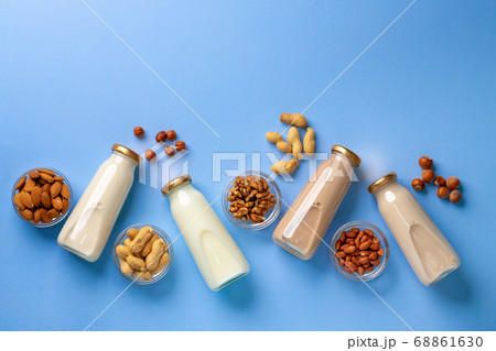 Bottles of vegan non dairy milk with various nuts on blue background Bottles of vegan non dairy milk with various nuts on blue background 68861630