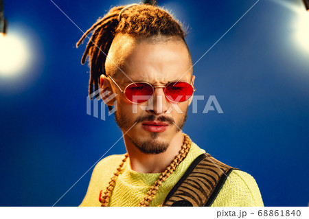 Portrait of a positive handsome caucasian guy with dreadlocks against blue background Portrait of a positive handsome caucasian guy with dreadlocks against blue background 68861840