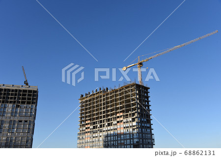 Tower crane working at construction site against blue sky background Tower crane working at construction site against blue sky background 68862131
