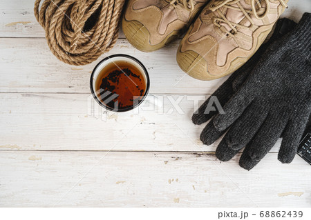Hiking boots with equipment for hiking, cup of tea on wooden board 68862439