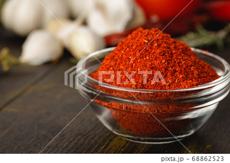 Red chili spice in glass bowl with herbs on dark table Red chili spice in glass bowl with herbs on dark table 68862523