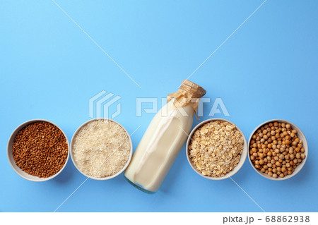 Vegetable milk concept with milk bottle and bowls with grains on blue background top view Vegetable milk concept with milk bottle and bowls with grains on blue background top view 68862938