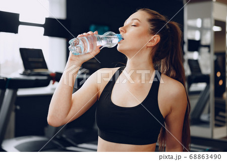 Young sporty woman drinking water in a gym Young sporty woman drinking water in a gym 68863490