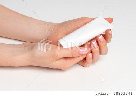 Female hand holding cosmetic bottle on white 68863541