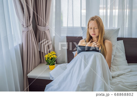 Woman talking by video call while lying in bed Woman talking by video call while lying in bed 68868802