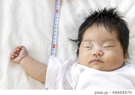 寝ている赤ちゃんと メジャーの目盛りの写真素材 6670