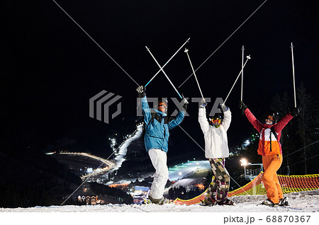 Cheerful friends skiing at ski resort at night. Cheerful friends skiing at ski resort at night. 68870367